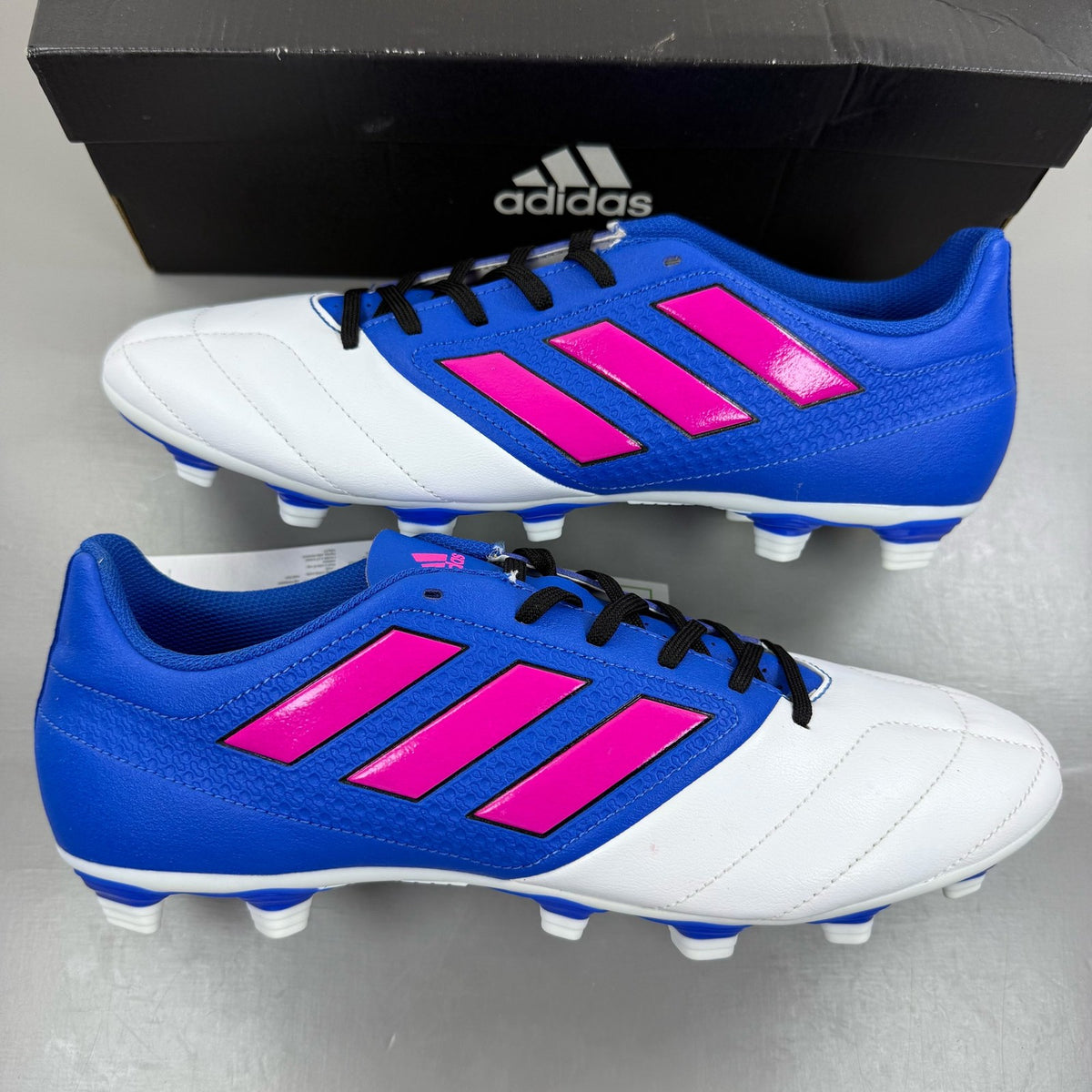 Adidas football boots white with blue and pink accents, featuring logo and textured material.