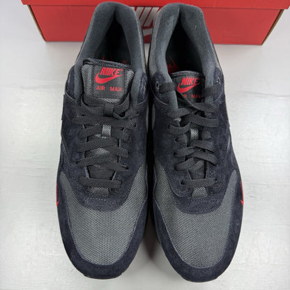 Nike Air Max 1 trainers black with red accents and logo detail on the side.