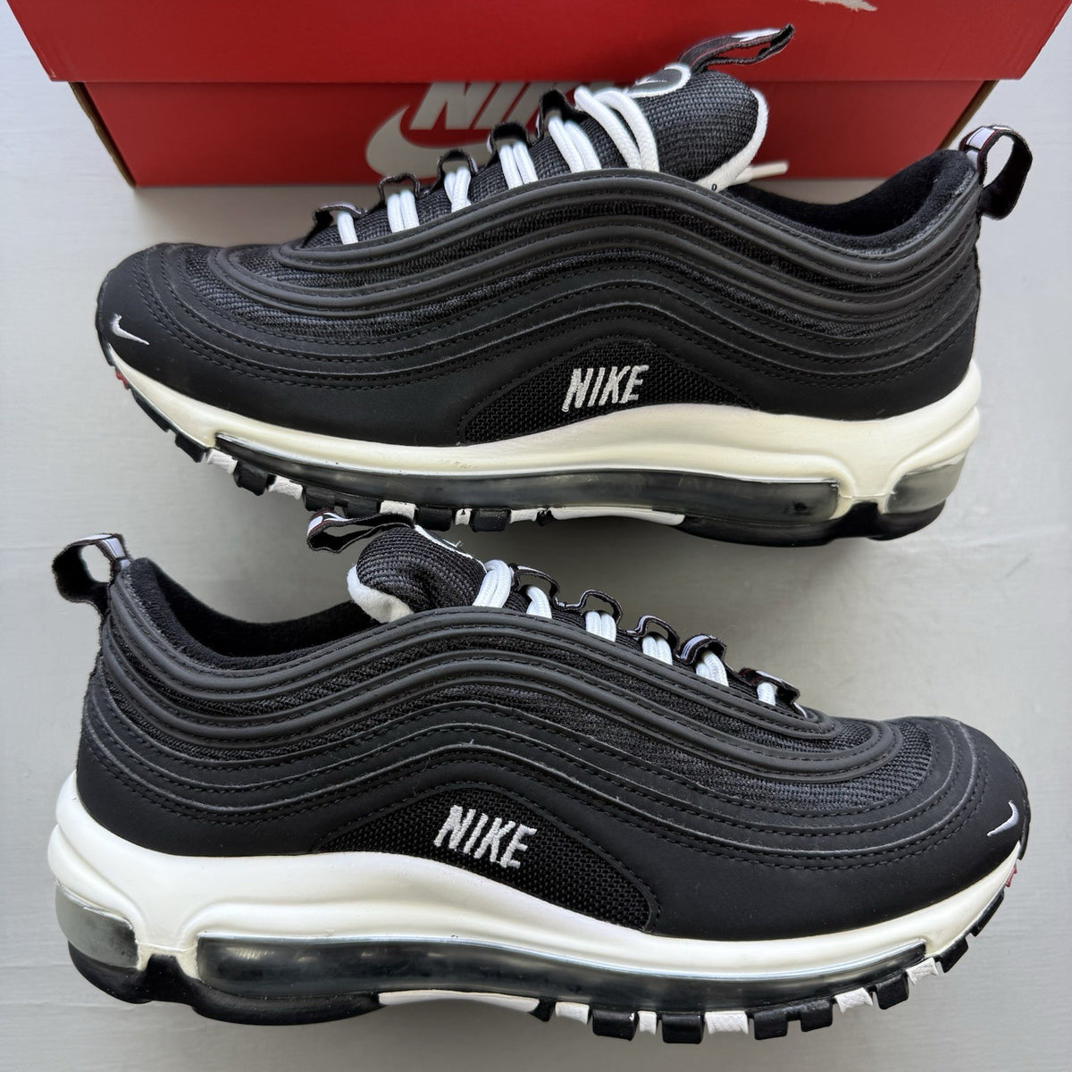 Nike Air Max 97 SE black trainers with white and varsity red accents, mesh and leather material.