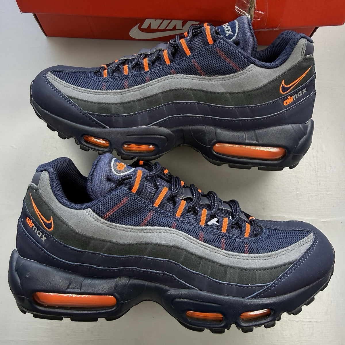 Nike Air Max 95 trainers navy blue with orange accents and anthracite grey details.