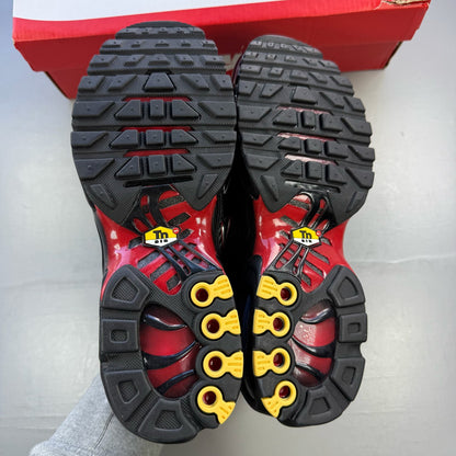Nike Air Max Plus TN black trainers with university red accents and visible logo details.