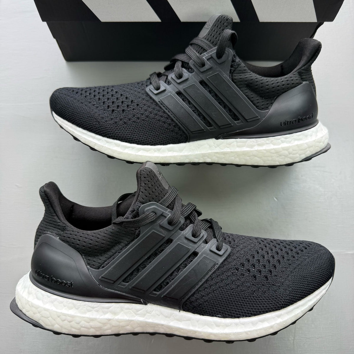 Adidas Ultraboost 1.0 black trainers with white accents and signature three-stripe logo.