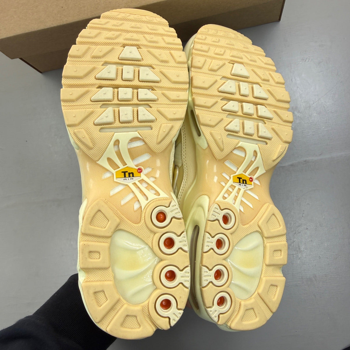 Nike Air Max Plus TN gold trainers with red and white accents, featuring iconic logo.