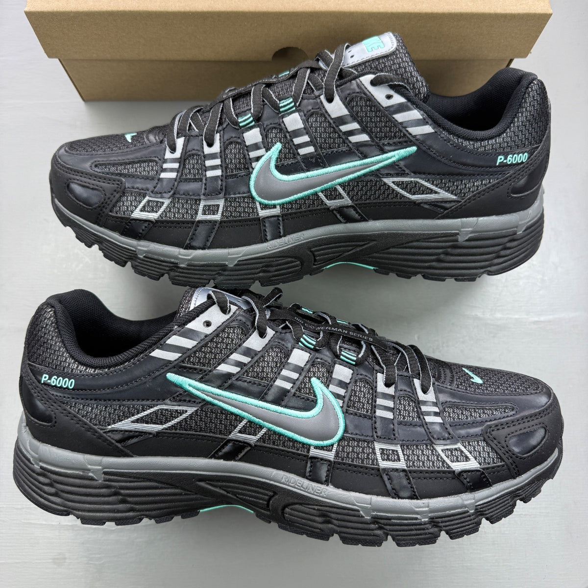 Nike black trainers with grey and turquoise accents, featuring a sleek mesh upper.