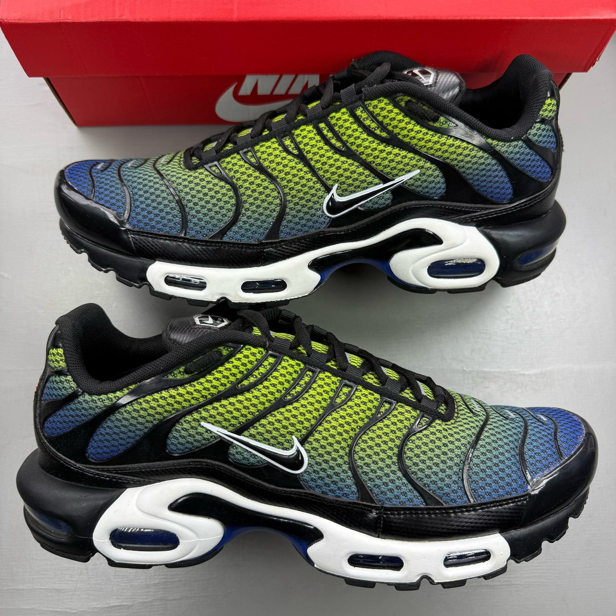 Nike Air Max Plus TN green trainers with black and volt accents, featuring signature logo.