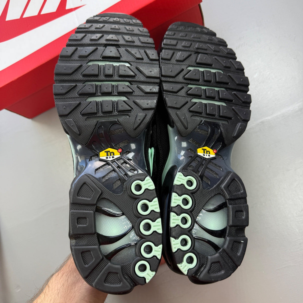 Nike Air Max Plus TN black trainers with mint green accents and signature logo.