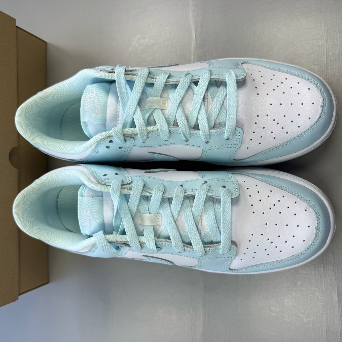 Nike Dunk Low trainers glacier blue and white with signature swoosh logo.