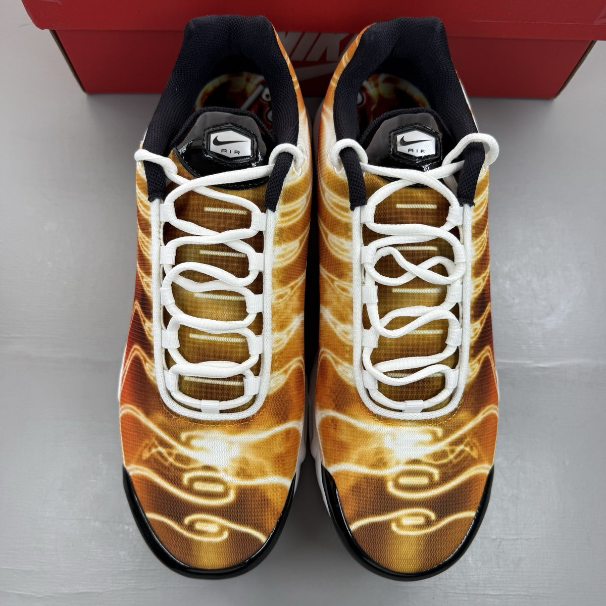 Nike Air Max Plus TN red trainers with signature logo and vibrant orange accents.