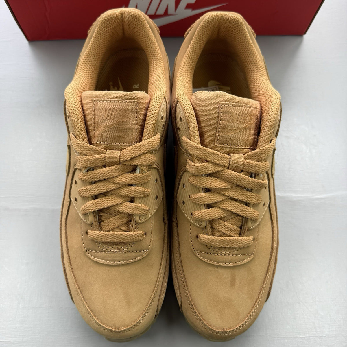 Nike Air Max 90 Premium beige trainers with gum sole and subtle branding details.