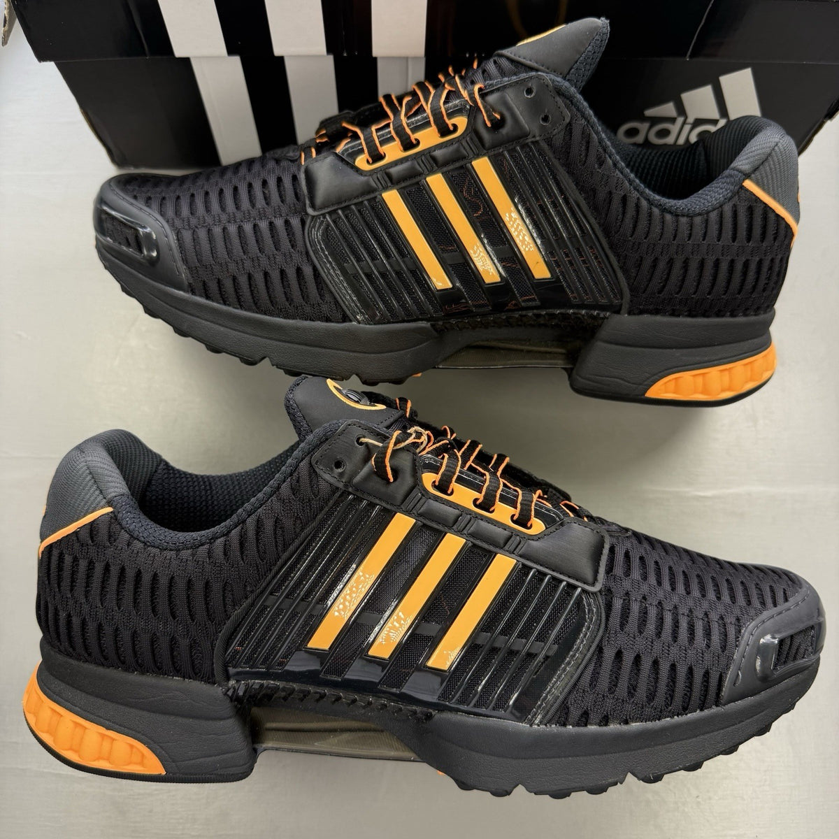 Adidas black trainers with flash orange accents and Climacool ventilation design.
