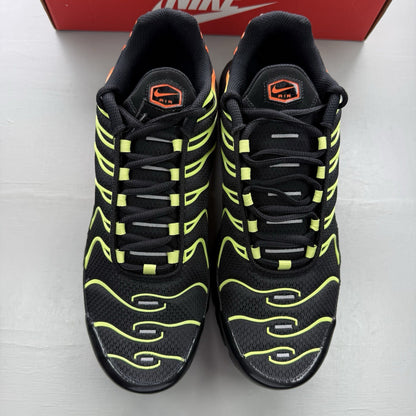 Nike Air Max Plus TN black trainers with vibrant orange and volt accents, mesh material.
