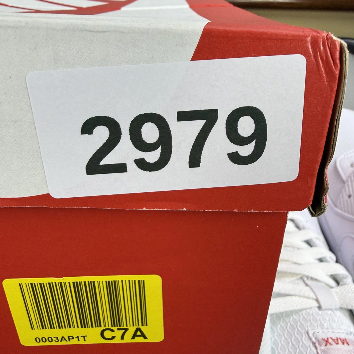 Nike Air Max 90 white trainers with light crimson accents and signature swoosh logo.