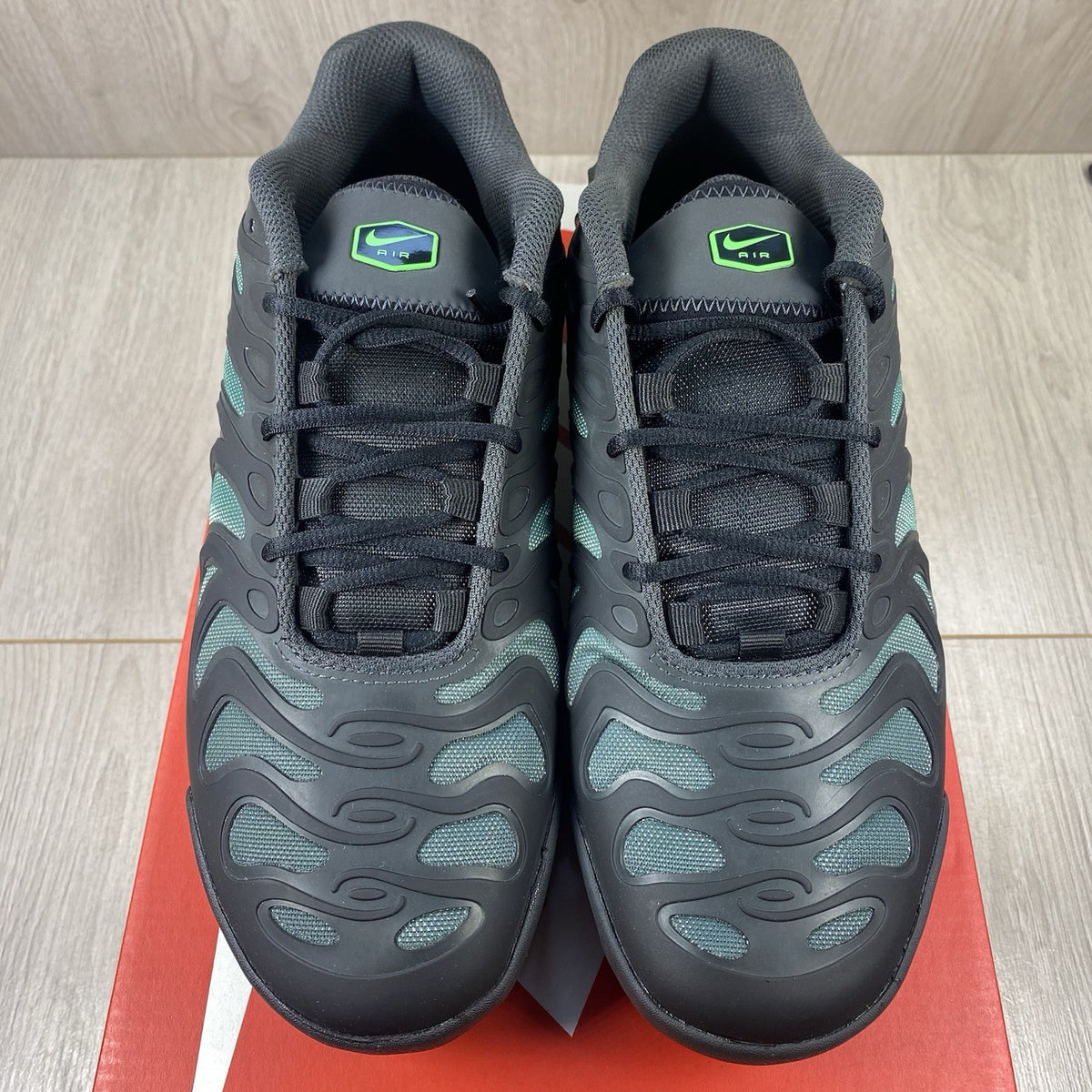 Nike Air Max Plus trainers black with volt green accents and signature swoosh logo.