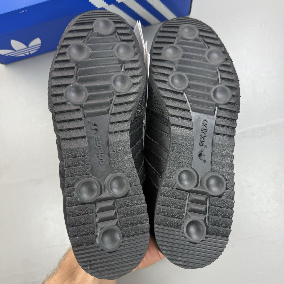 Adidas Samba Super black trainers with white and gold logo detailing.