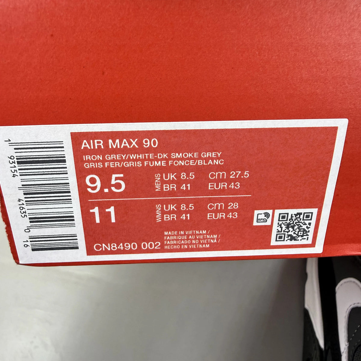 Nike Air Max 90 grey trainers with black and white accents, featuring logo details.