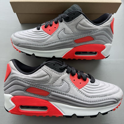 Nike Air Max 90 grey trainers with bright crimson accents and black detailing.