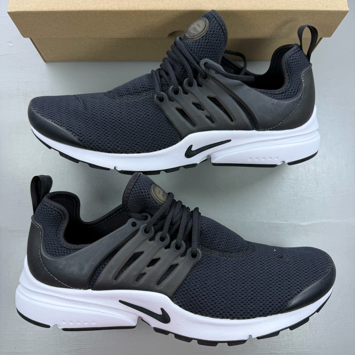 Nike Air Presto black trainers with white accents and breathable mesh upper.