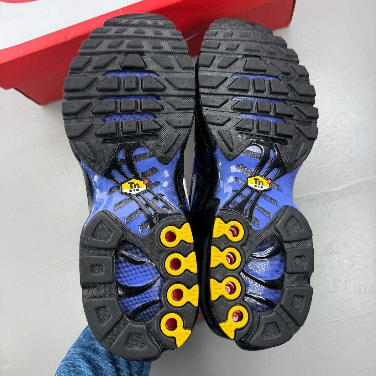 Nike Air Max Plus TN black trainers with sapphire blue accents and signature logo.
