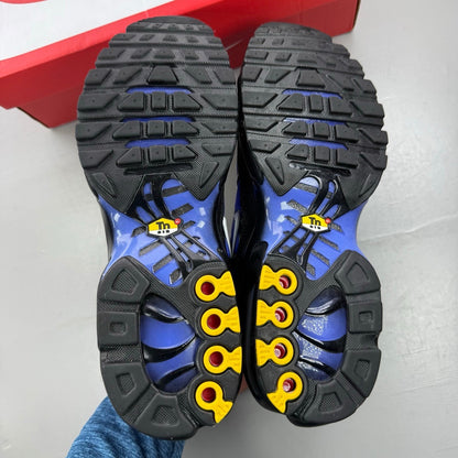 Nike Air Max Plus TN black trainers with sapphire blue accents and signature logo.