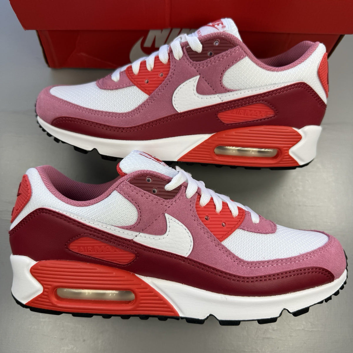 Nike Air Max 90 red trainers with white accents and signature swoosh logo.