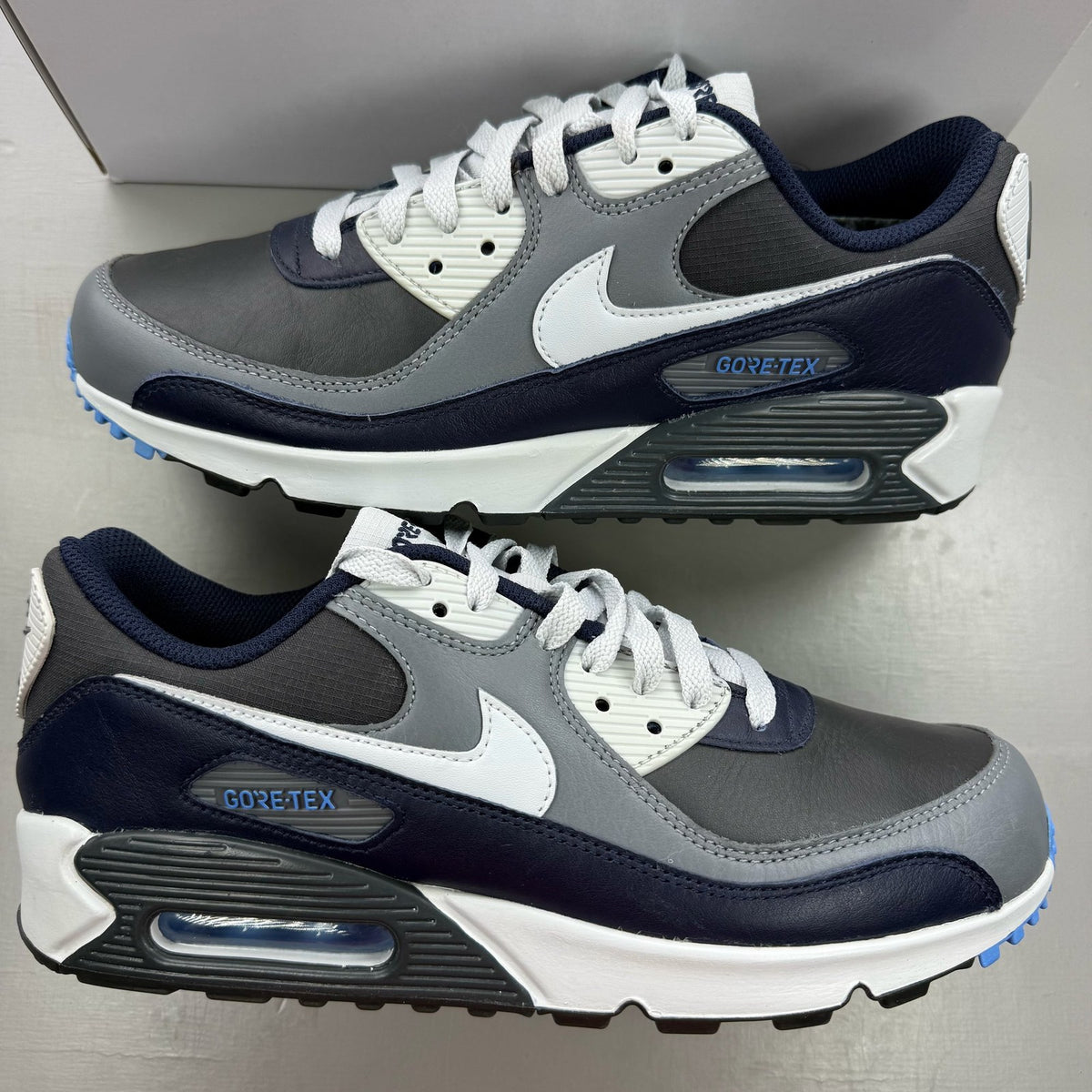 Nike Air Max 90 grey trainers with GORE-TEX material and logo detailing.