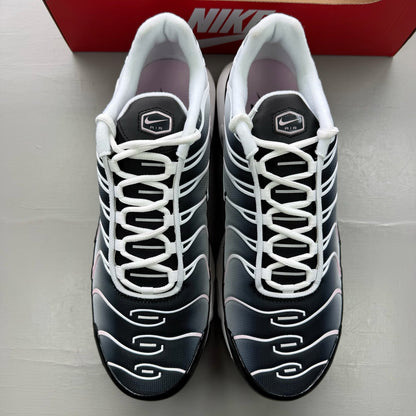 Nike Air Max Plus TN black trainers with pink accents and signature swoosh logo.