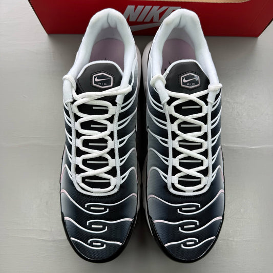 Nike Air Max Plus TN black trainers with pink accents and signature swoosh logo.