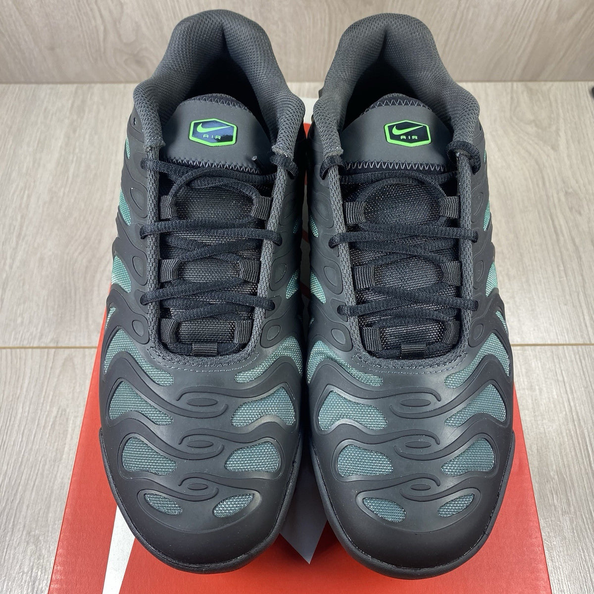 Nike Air Max Plus trainers black with volt green accents and signature swoosh logo.
