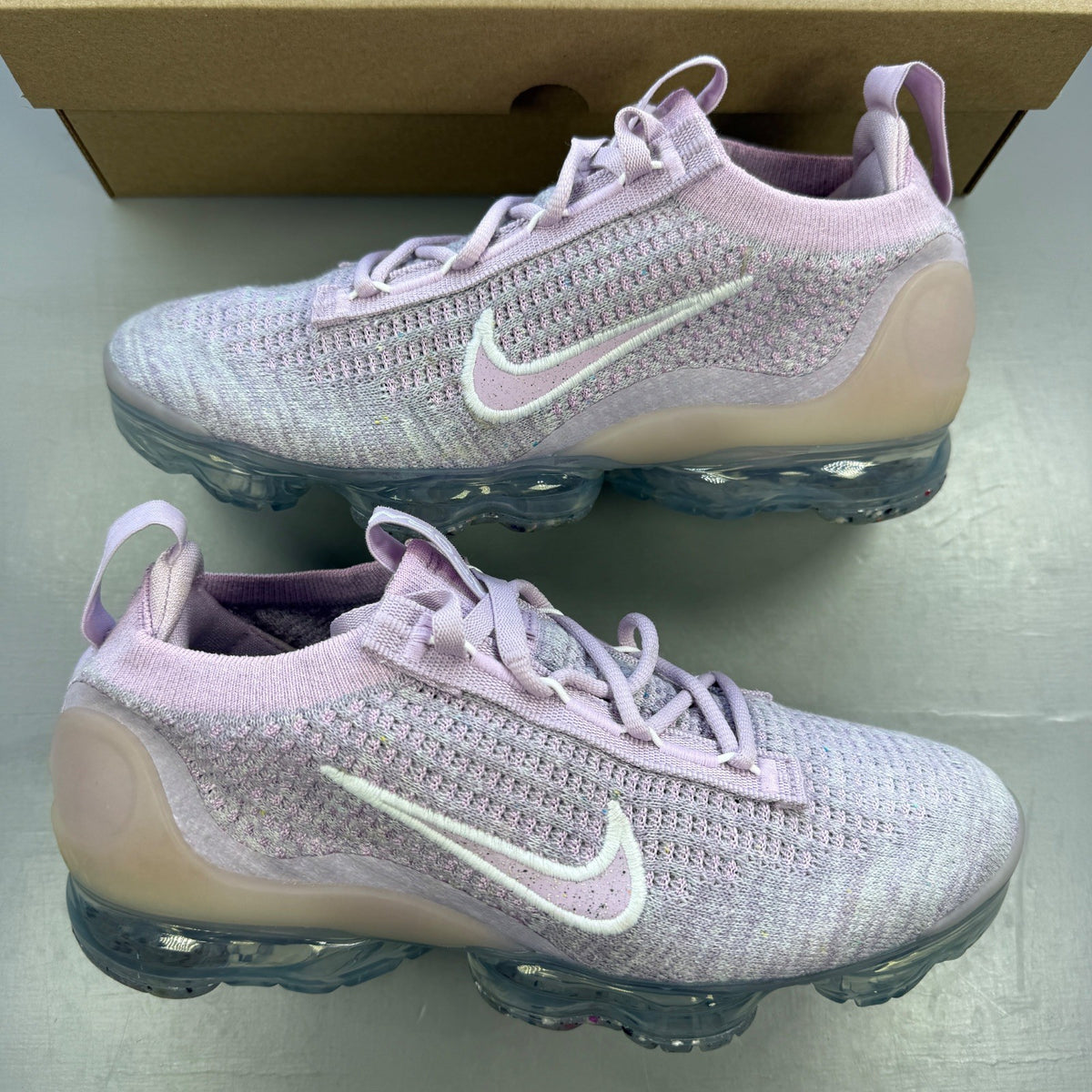 Nike trainers pink Flyknit upper with Air cushioning and logo detail.