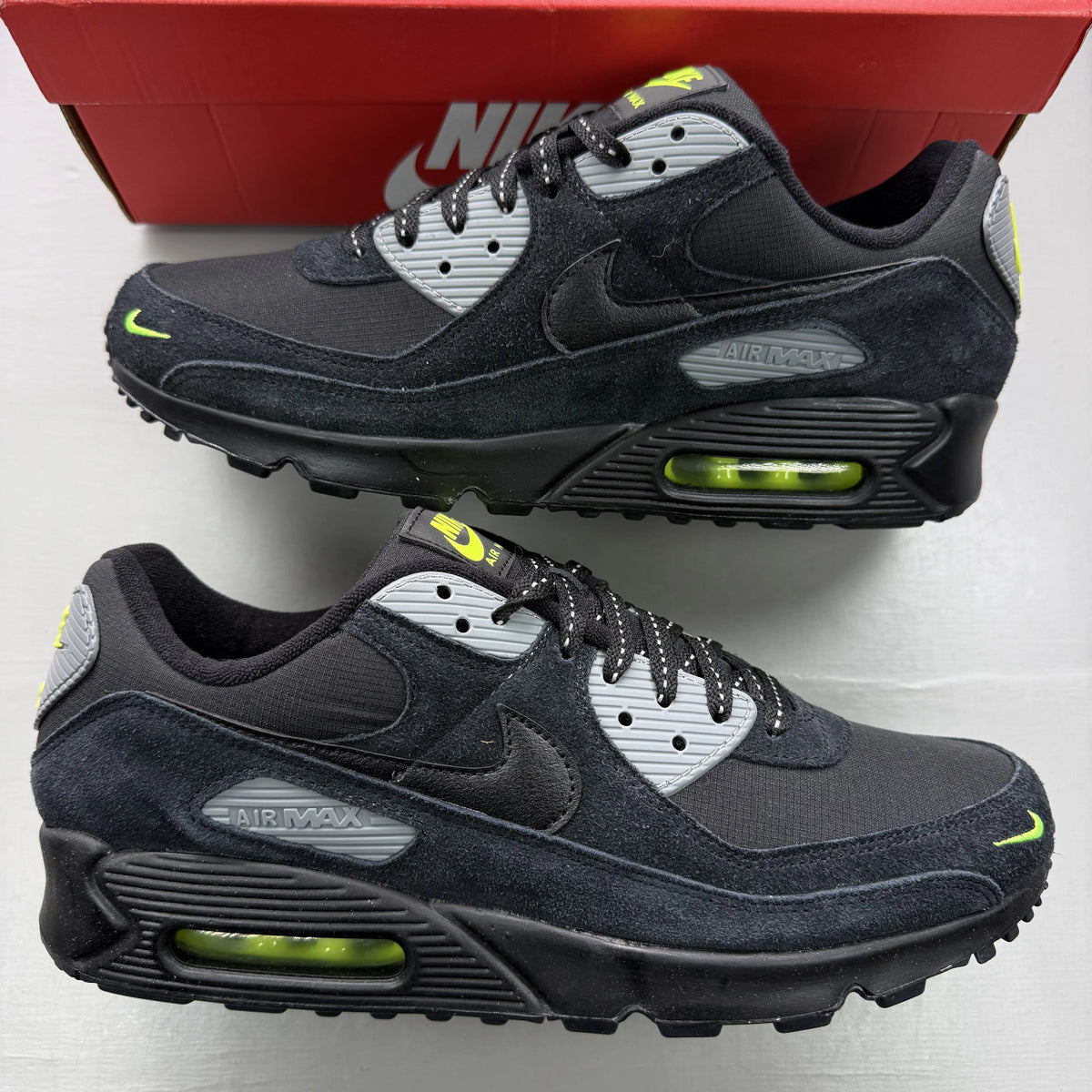 Nike Air Max 90 black trainers with volt and cool grey swoosh logo.