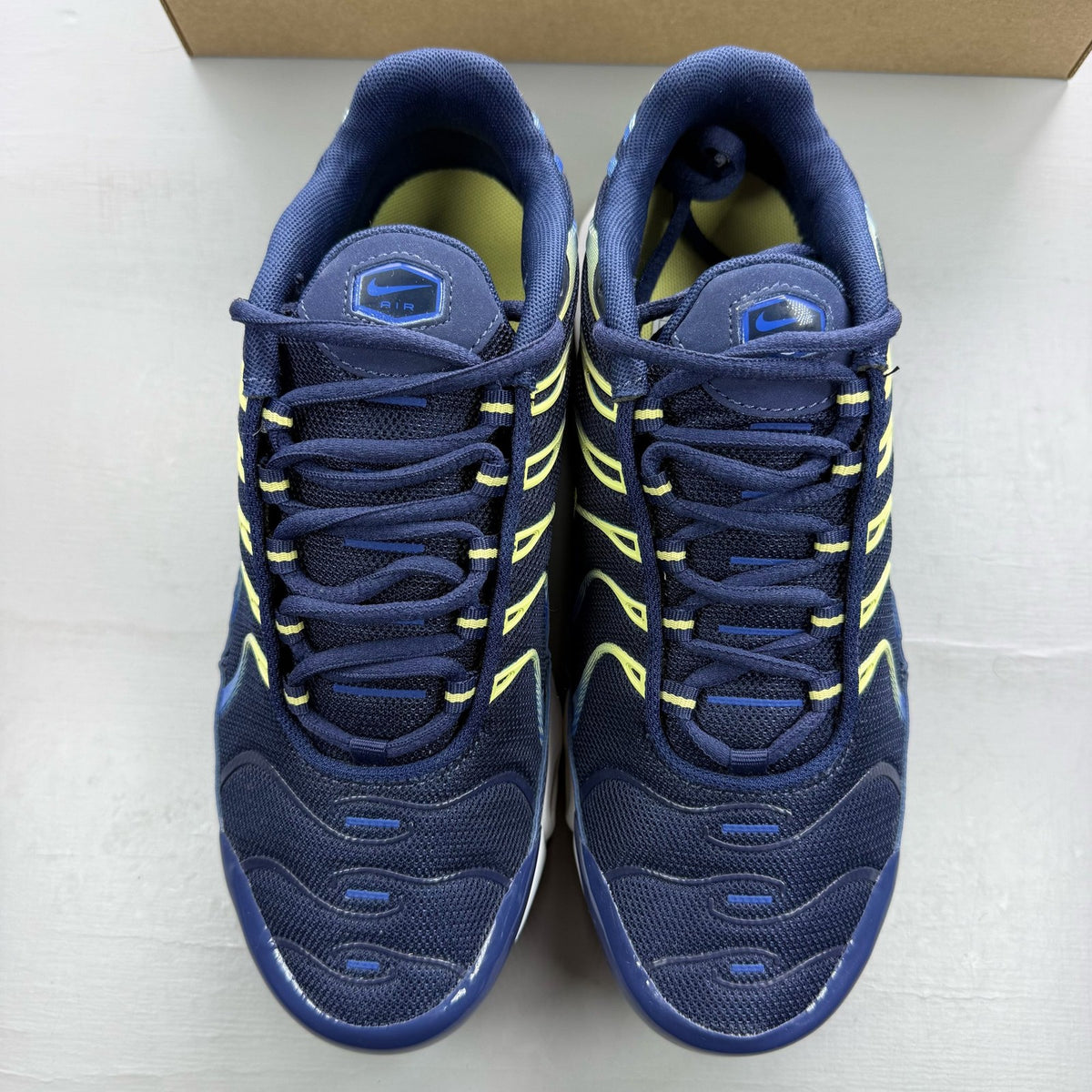 Nike Air Max Plus TN blue trainers with yellow accents and signature swoosh logo.