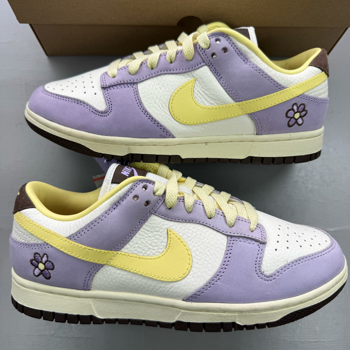 Nike Dunk Low purple trainers with soft yellow accents and classic swoosh logo.
