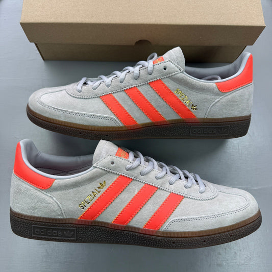 Adidas grey trainers with coral accents and gum sole, featuring classic logo.