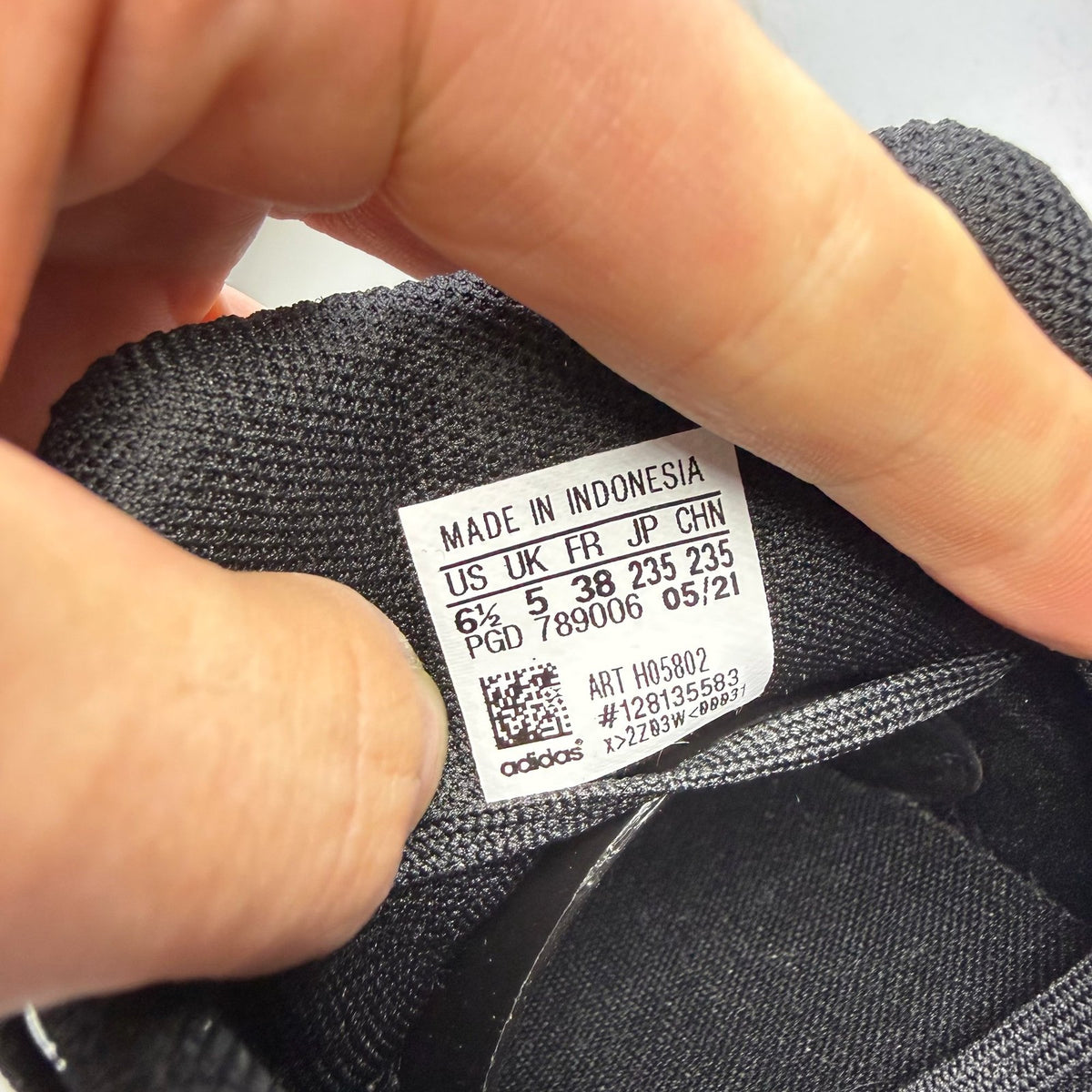 Adidas black trainers with signature three stripes and cushioned sole.