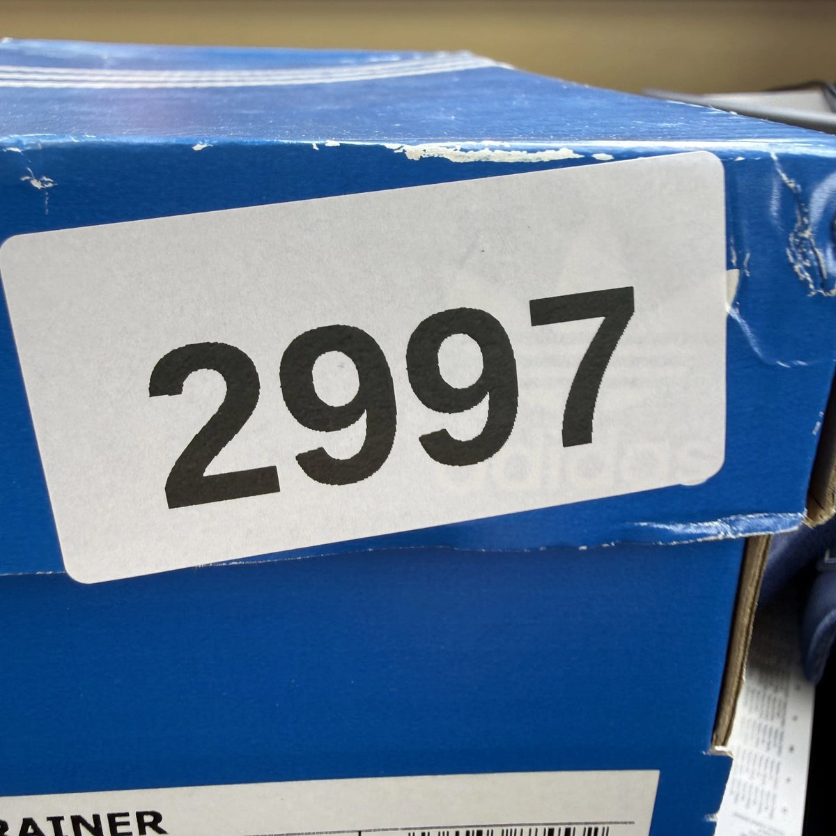 Adidas blue LA Trainer sneakers with white stripes and logo detailing.