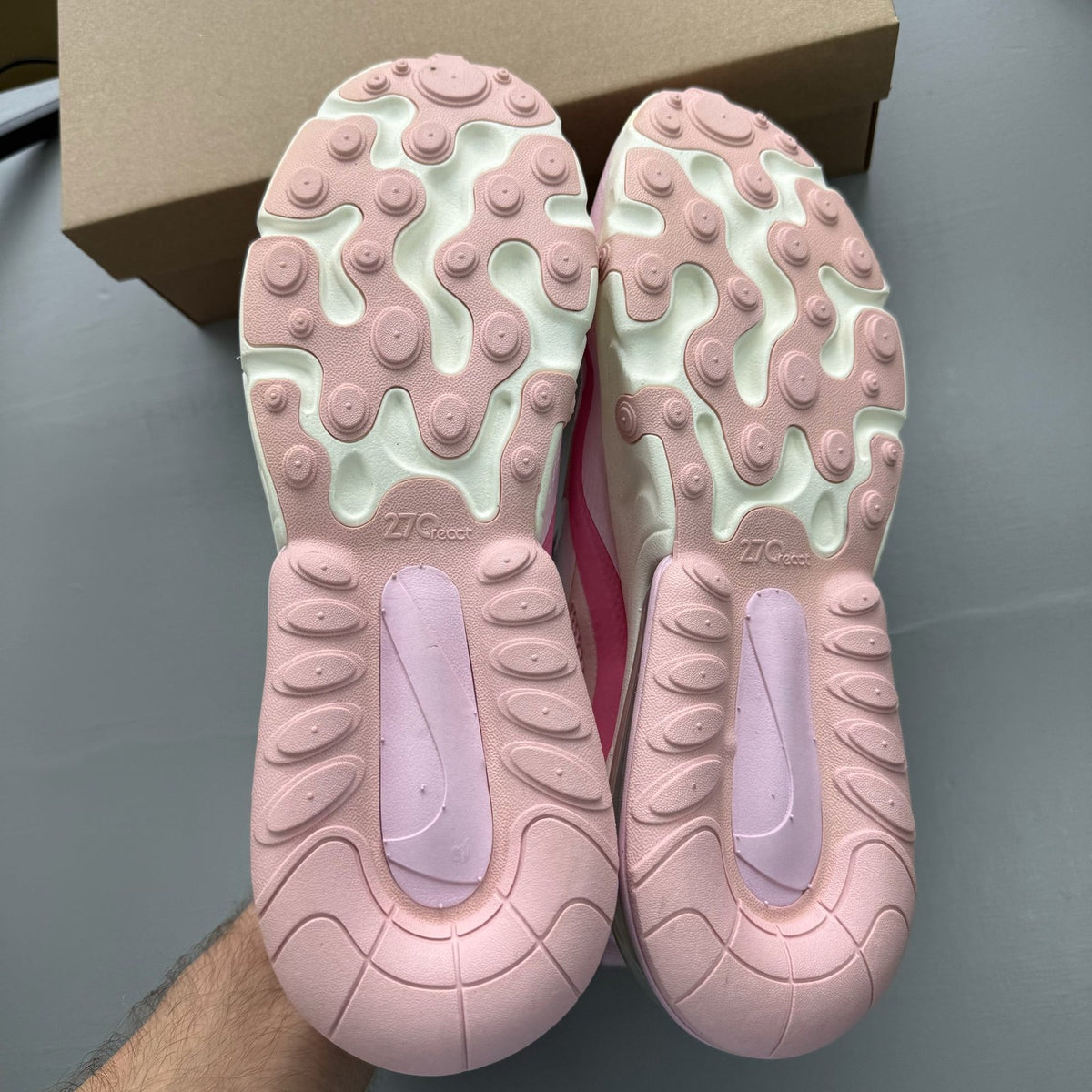 Nike Air Max 270 React white trainers with pink accents and logo detail.