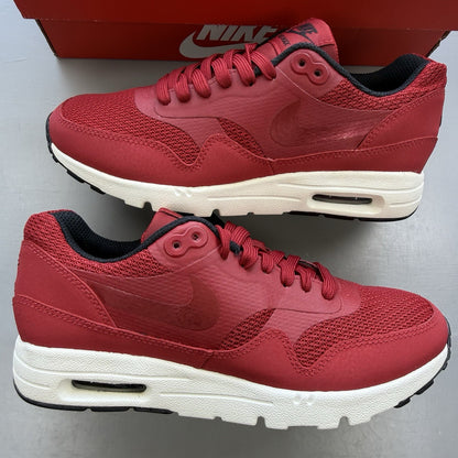 Nike Air Max 1 Ultra Essential red trainers with white and black accents, logo detail.