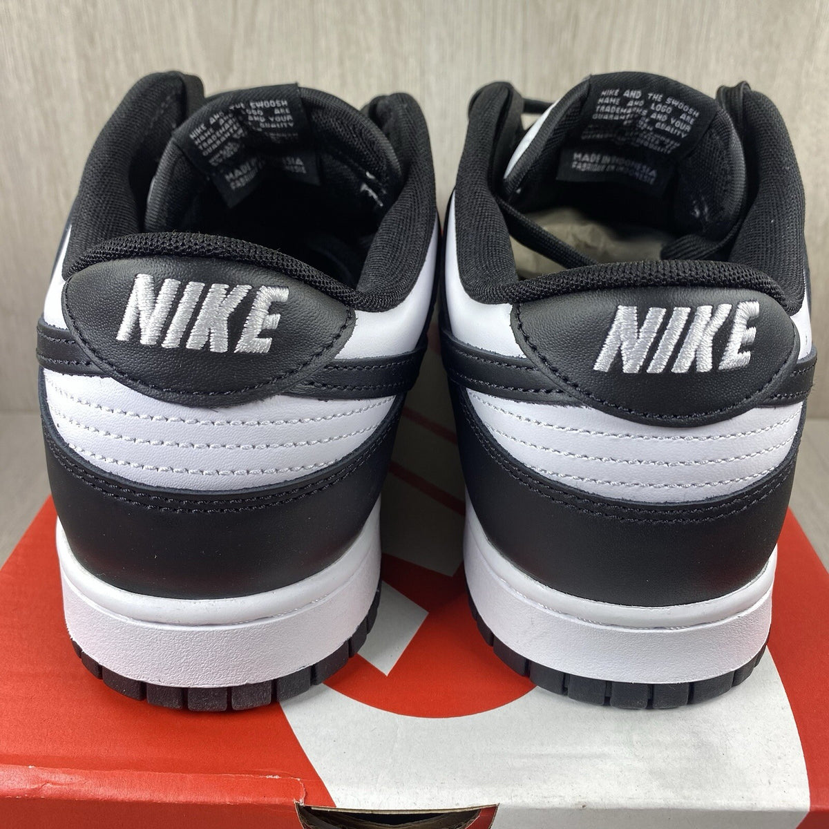 Nike Dunk Low trainers black and white with iconic swoosh logo and smooth leather upper.