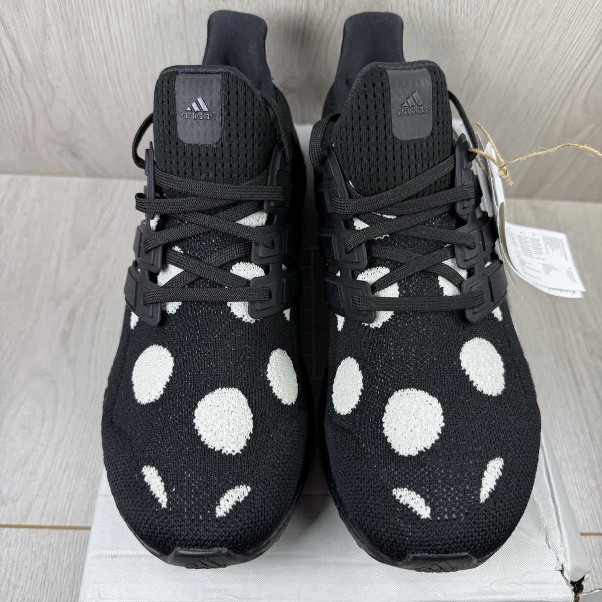 Adidas black trainers with white polka dot pattern and iconic three-stripe logo.