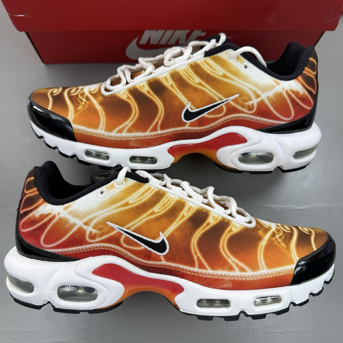 Nike Air Max Plus TN red trainers with signature logo and vibrant orange accents.