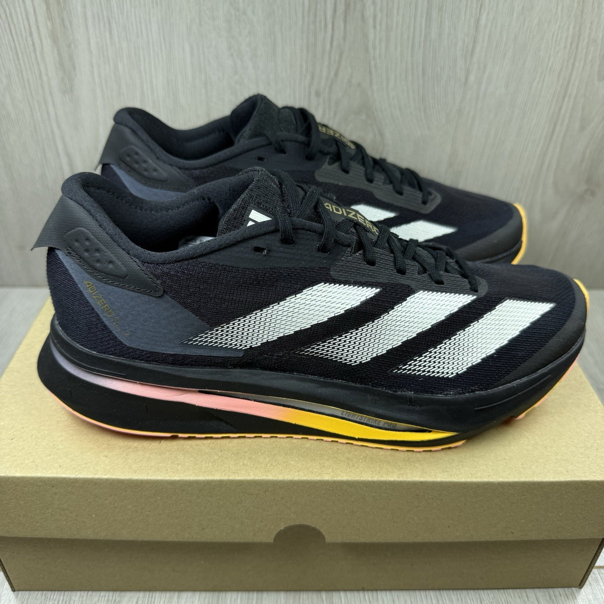 Adidas black trainers with white accents and distinctive Adizero branding.