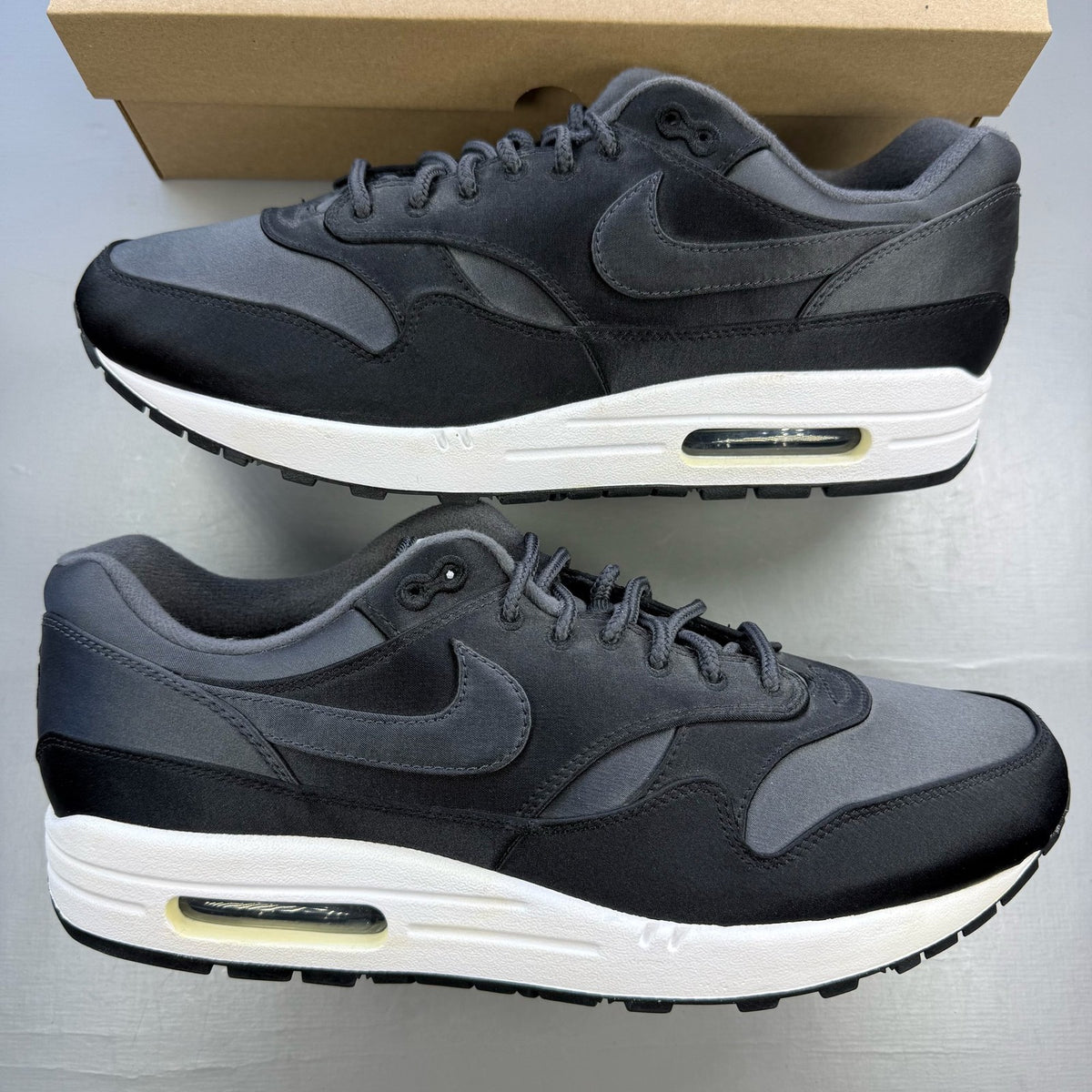 Nike black trainers with satin finish and pinwheel design details.