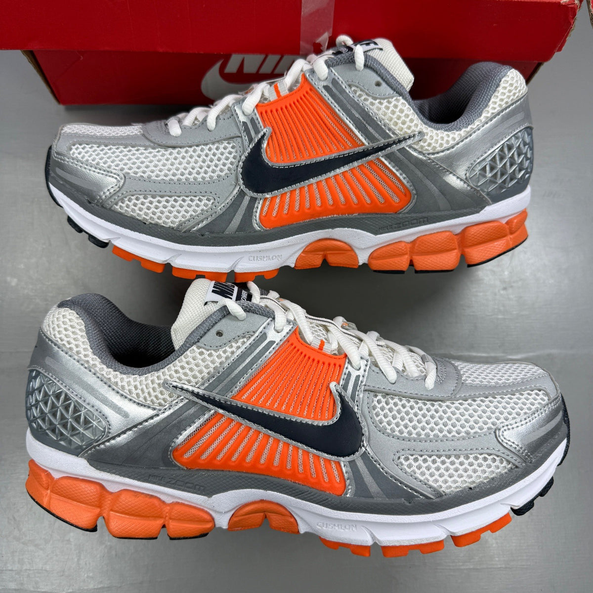 Nike running shoes orange with grey accents and distinctive logo detailing.