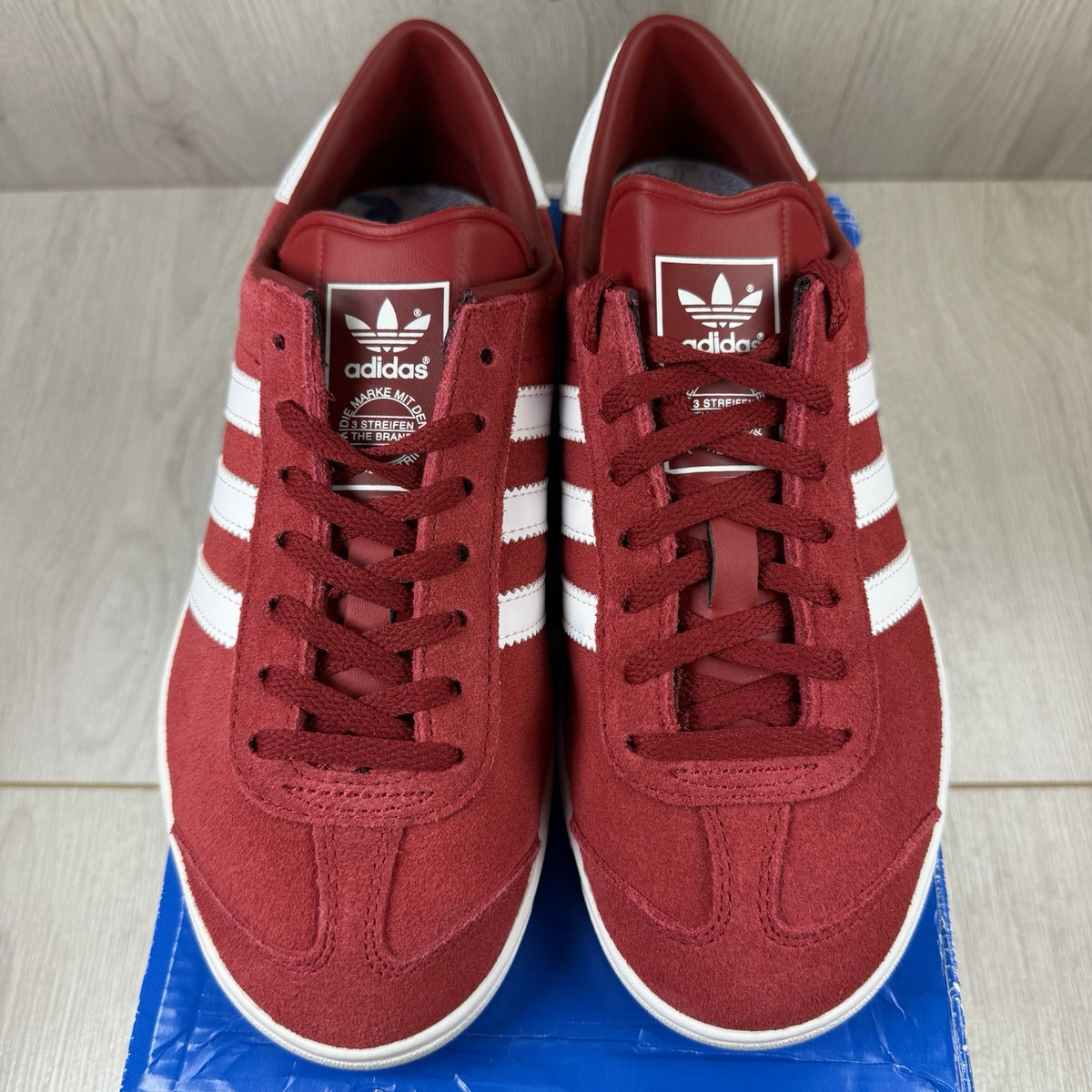 Adidas red trainers with white stripes and logo, classic suede material.