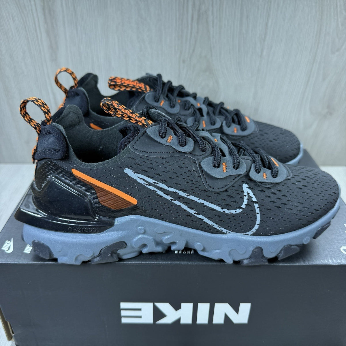 Nike React Vision black trainers with safety orange accents and unique design details.
