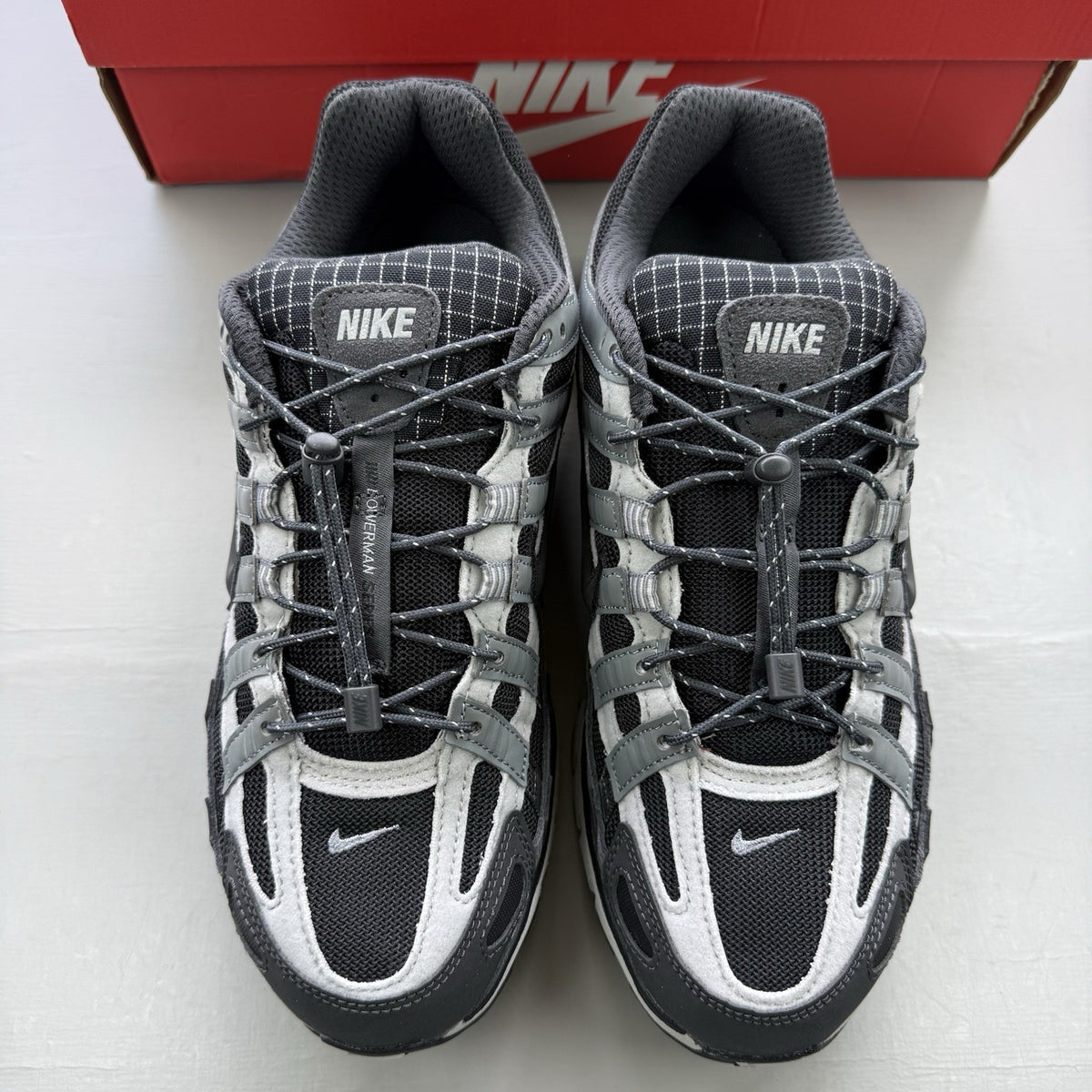 Nike black trainers with grey accents and reflective detailing, featuring a classic logo.