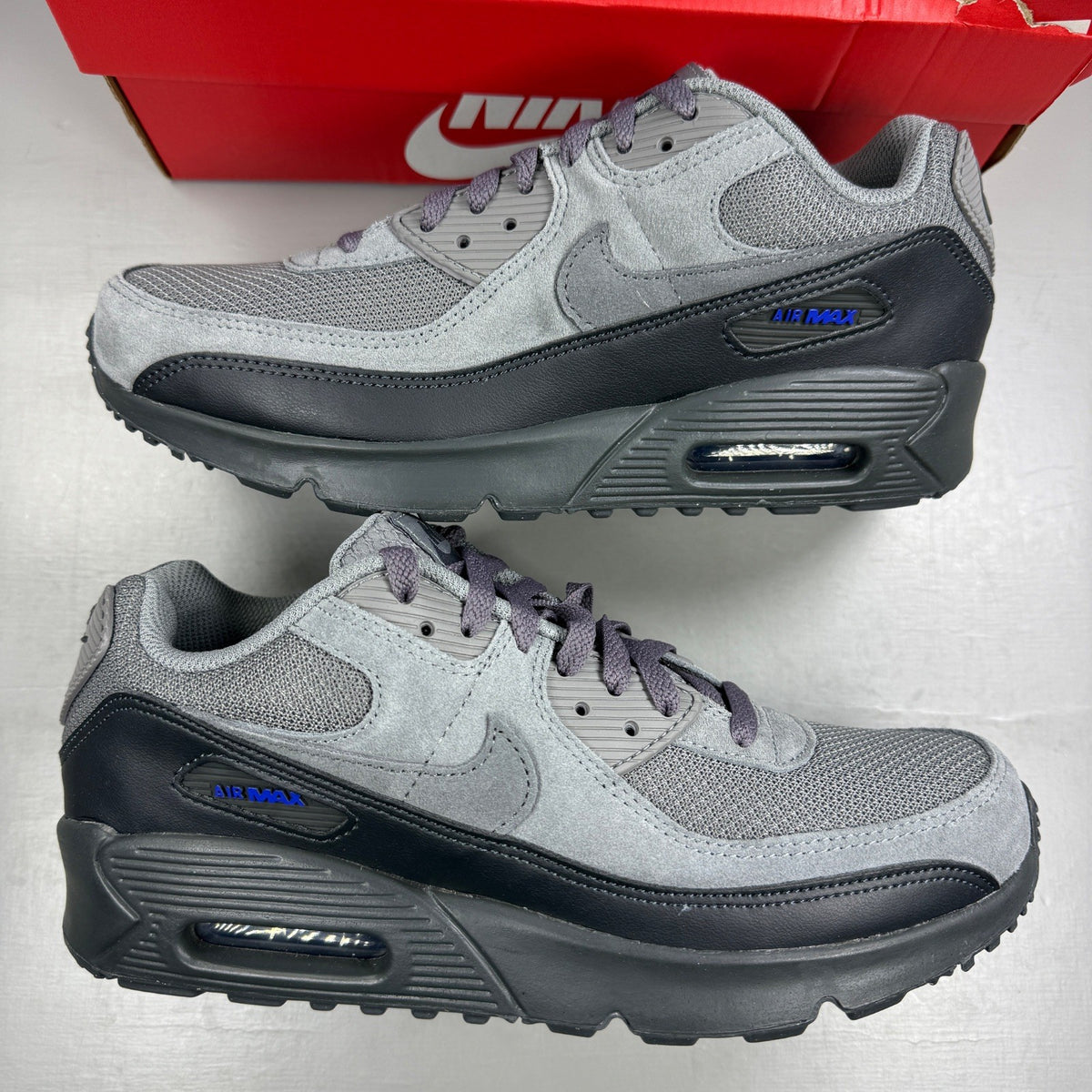 Nike Air Max 90 Tech grey trainers with blue accents and logo detail.