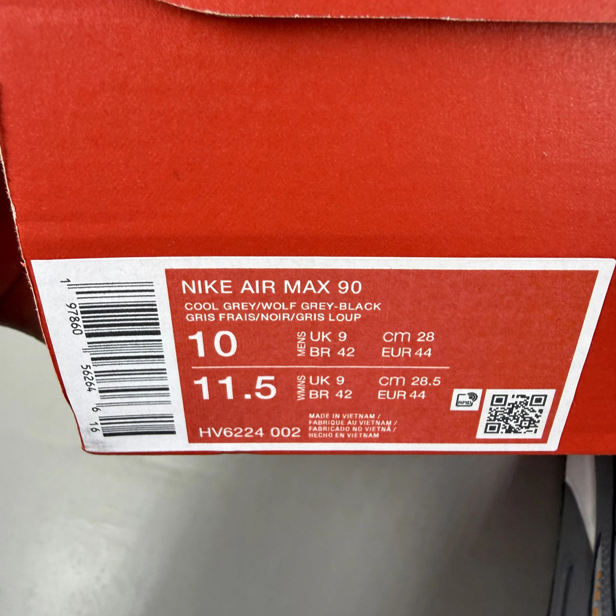 Nike Air Max 90 grey trainers with black and sundial accents, featuring logo details.
