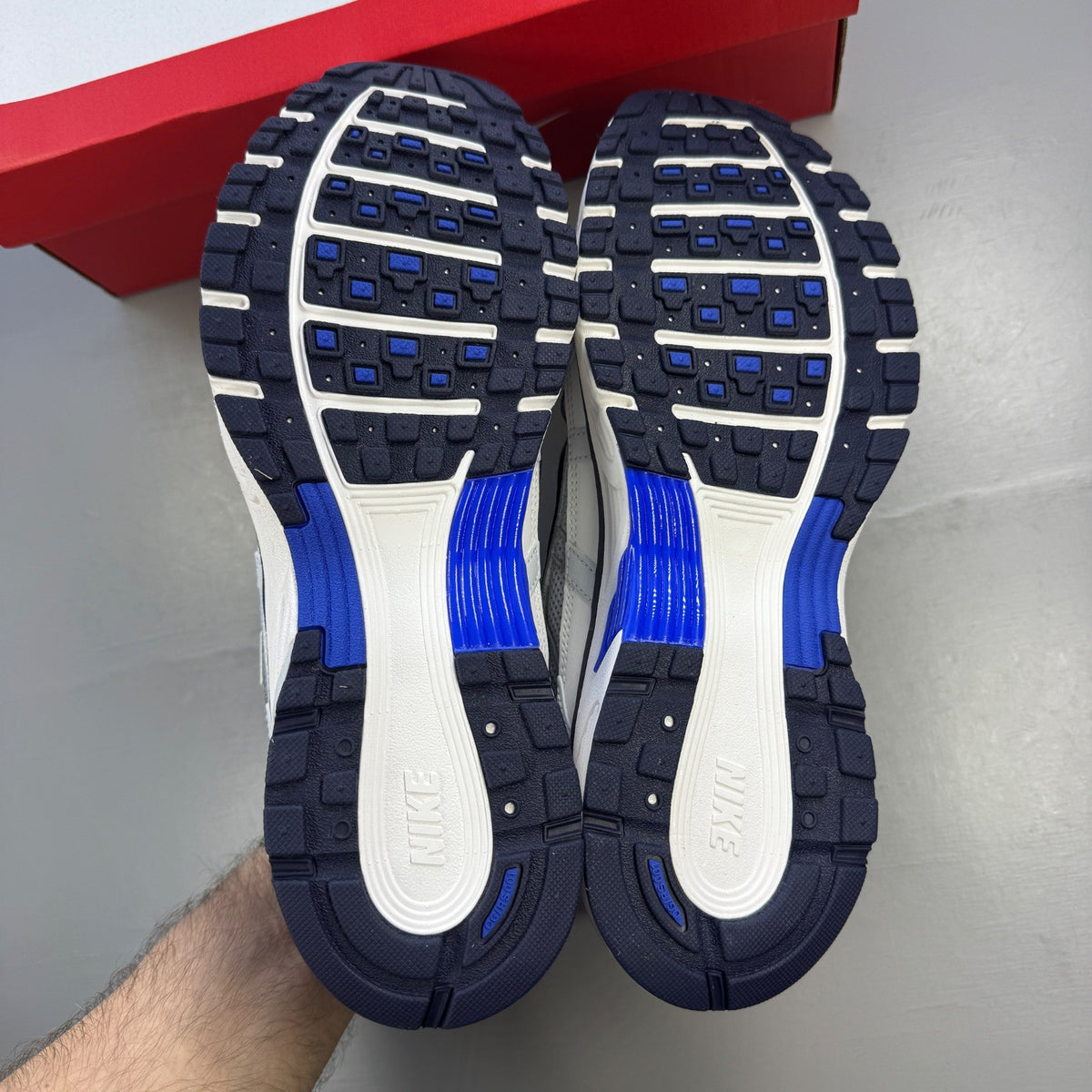Nike P-6000 grey trainers with blue and white accents, featuring logo detail.