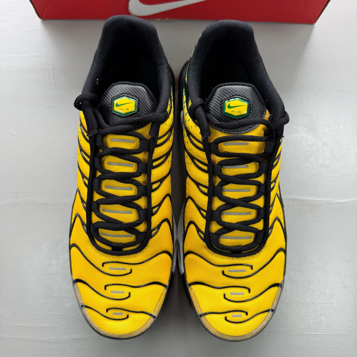 Nike black trainers featuring Air Max Plus design and vibrant yellow accents.